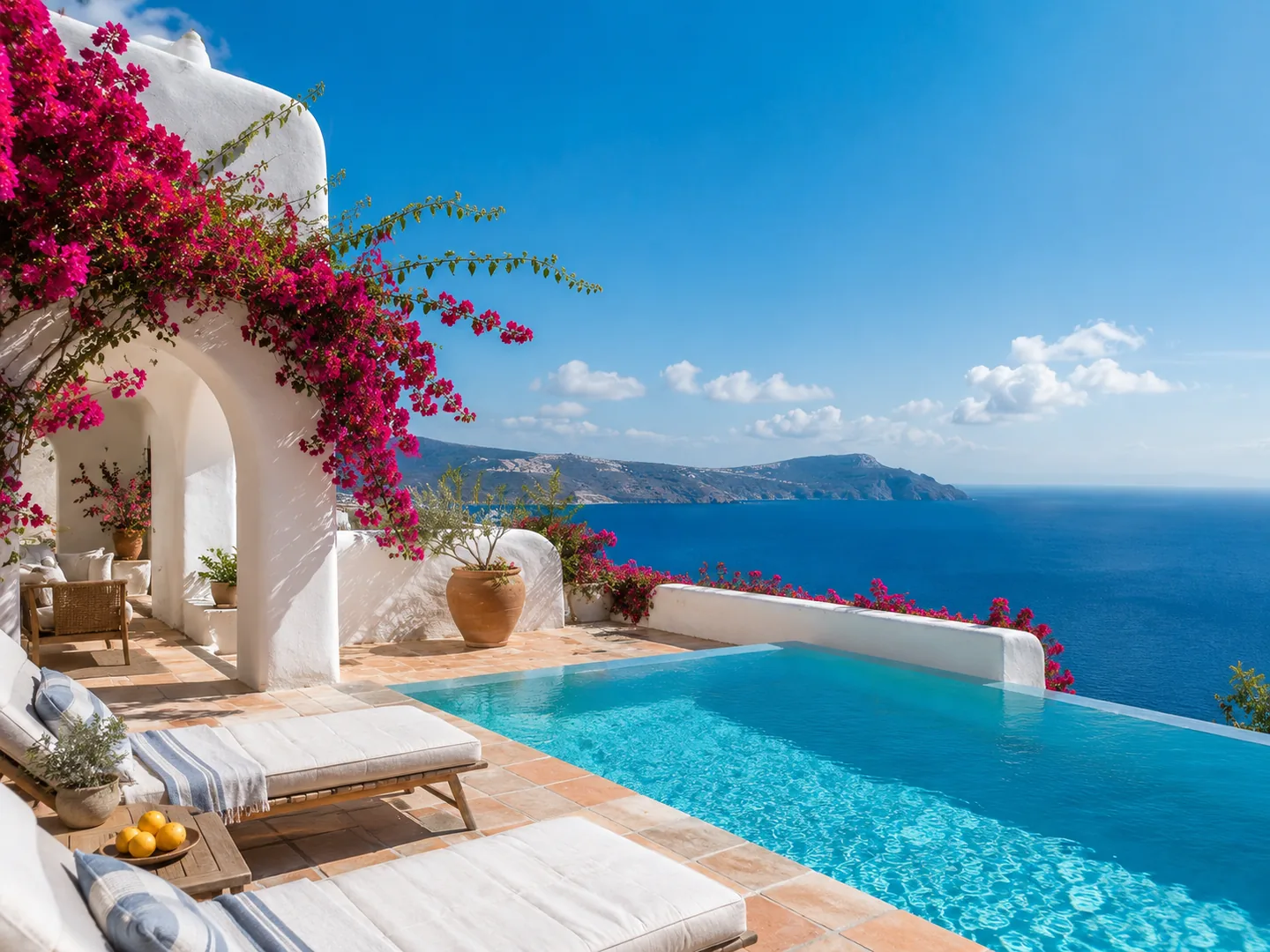 A whitewashed villa terrace with an infinity pool overlooking the sea
